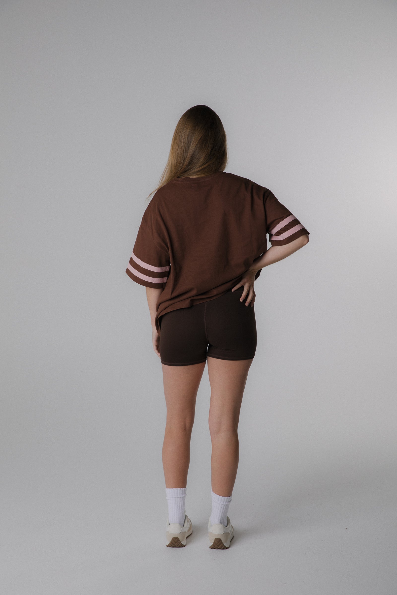 Woman wearing brown with pink stripes on the sleeve oeko-tex oversized cotton tee back view